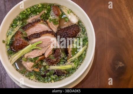 Vietnamesisches Pho mit Ente mit knuspriger Haut, grünen Zwiebeln und Kräutern Stockfoto