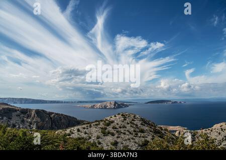 Atemberaubende Aussicht auf die kroatische Küste mit felsigen Hügeln, ruhigem blauem Wasser und einem weiten Himmel voller flauschiger Wolken. Eine ruhige Momente Stockfoto