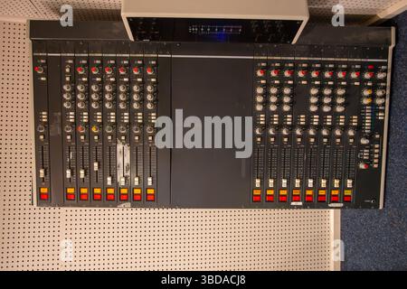In einem Aufnahmestudio ist eine professionelle Soundmischkonsole mit verschiedenen Drehknöpfen und Schiebereglern eingerichtet. Stockfoto