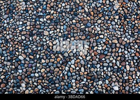 Steine in verschiedenen Formen, Größen und Farben an der Küste, Nahaufnahme. Hintergrund von Meeressteinen. Stockfoto