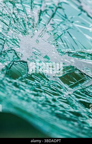 Nahaufnahme einer zersplitterten Windschutzscheibe mit filigranen Rissen. Grüngetöntes Sicherheitsglas, das durch Aufprall gebrochen wurde. Stockfoto