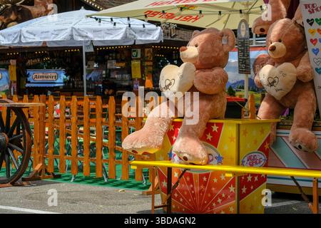 Das Bild zeigt eine festliche Outdoor-Szene mit großen Teddybären, die Herzkissen halten, auf denen „I love you“ steht. Diese kuscheligen Figuren Stockfoto
