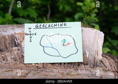 Geocaching, Freizeitaktivitäten im Freien, Navigation zum Verstecken und Suchen von Containern, Geocache-Standort im Wald, Schatzjagd-Spiel, Hinweis auf Baum tr Stockfoto
