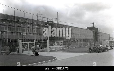 1960er Jahre, historische, neue Großbüros im Bau in einem Industriegebiet in Whitney, Oxford, England, Großbritannien. Sie parken draußen bei einer Werkshütte, verschiedene Motorfahrzeuge, darunter ein dreirädriges Bubble-Auto, ein Motorrad mit Beiwagen, Roller und Treträder. Stockfoto