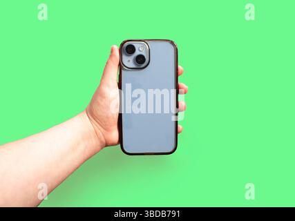 Smartphone mit alter und schmutziger transparenter Handyhülle in der Hand auf lebendigem Hintergrund, die vor und nach dem Gebrauch illustriert und eine effektive visuelle Geschichte ermöglicht Stockfoto