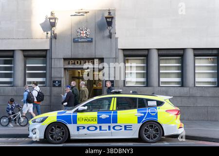 Ein gekennzeichnetes Polizeiauto der City of London, das vor dem Bahnhof geparkt wurde, und Fußgänger kümmern sich um ihre eigenen Angelegenheiten auf dem Bürgersteig in der belebten Central London Street in Großbritannien Stockfoto