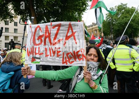 London, Großbritannien. 23. Mai 2025. Eine Frau hält ein Banner mit der Aufschrift „Gaza will 4 Ever leben“, während Aktivisten eine kurze Straßensperre inszenieren, während eine Koalition palästinensischer Anhänger in Whitehall, gegenüber der Downing Street-Residenz des britischen Premierministers Sir Keir Starmer, protestiert und ein Ende des Waffenverkaufs an Israel fordert. Obwohl der israelische Staatschef Benjamin Netanjahu vom Internationalen Strafgerichtshof wegen Kriegsverbrechen und Verbrechen gegen die Menschlichkeit gesucht wird, werden die Waffenlieferungen in Großbritannien fortgesetzt. Quelle: Ron Fassbender/Alamy Live News Stockfoto