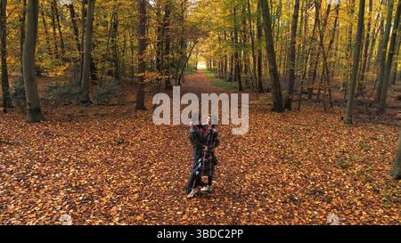 Ein junges Paar, das eine romantische Zeit hat und sich im Wald ansieht. Der Blick auf die schöne Frau und den hübschen Mann hat einen schönen Blick auf den malerischen Herbst Stockfoto