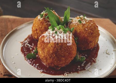 Knusprige Arancini-Vorspeise mit Parmesan und Mikrogrün, Teller, Tomatensauce, hausgemacht, keine Leute Stockfoto