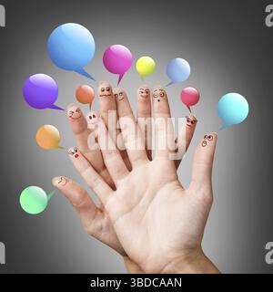 Fröhliche Finger-Smileys mit bunten Sprechblasen auf grauem Hintergrund Stockfoto