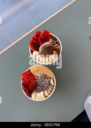 Blick aus der Vogelperspektive auf zwei Acai Schalen, die nebeneinander auf einem Tisch in einem Acai Shop sitzen Stockfoto