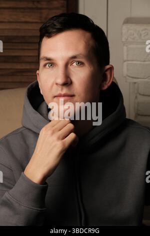 Ein junger Mann in einem stylischen Hoodie strahlt ein entspanntes, mutiges Auftreten aus und zeigt seine Persönlichkeit Stockfoto
