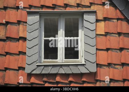 Oberlicht mit Schieferrahmen in einem Gebäude, das mit roten Dachziegeln bedeckt ist Stockfoto
