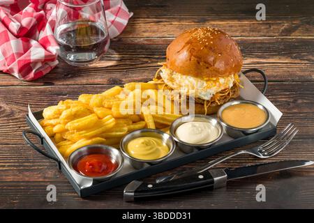 Eierburger mit knusprigen Kartoffeln serviert mit Pommes und Saucen Stockfoto