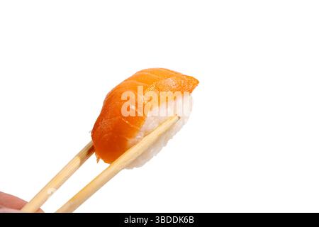 Nigiri mit Stäbchen gehalten. Ein einzelner Lachsnigiri wird zwischen zwei Bambus-Essstäbchen gehalten. Die Textur des Lachses glänzt appetitlich und betont Stockfoto