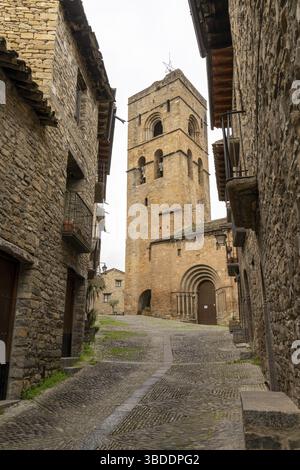 Vertikaler Blick auf eine schmale Kopfsteinpflasterstraße mit massivem Braun Steinhäuser und Steinkirche an der Spitze Stockfoto