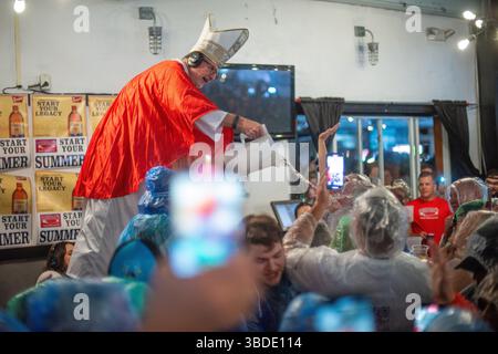 North Wildwood, Usa. Mai 2025. Preston Elliot, gekleidet als Papst, gibt den jährlichen „Segen des Biers“ während der WMMR Preston and Steve Show der Jersey Shore anlässlich des Memorial Day Weekend Freitag, 23. Mai 2025 im Keenan's Irish Pub in North Wildwood, New Jersey. Seit über 20 Jahren sendet die Radioshow aus Philadelphia live im Keenan's, um die Sommersaison zu starten. Dieses Jahr wurde die Veranstaltung von Coors Banquet gesponsert. William Thomas Cain/Alamy Live News Stockfoto
