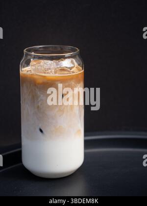 Tasse Kaffee in klarem, langem Glas. Latte mit Eis und alternativer Milch. Leckeres erfrischendes Getränk Stockfoto