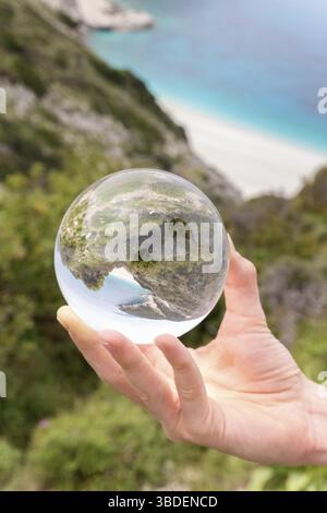 Hand, die Kristallkugel in der Nähe von Strand und Bergen Stockfoto