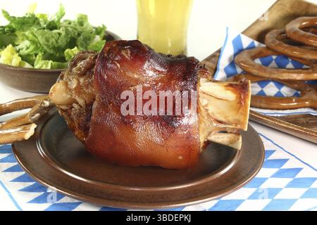 Frische Schweinshaxe mit Weizenbier, Brezeln und Salat Stockfoto