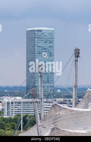 München, Deutschland. Mai 2025. Der O2 Tower in München (Bayern). Die Olympiaanlage im Olympiapark mit dem Olympiastadion ist im Vordergrund zu sehen. O2 ist die Marke des Telekommunikationsunternehmens Telefonica. Mit dem O2-Netz (Telefonica-Netz) betreibt Telefonica das billigste Mobilfunknetz Deutschlands Credit: Matthias Balk/dpa/Alamy Live News Stockfoto