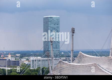 München, Deutschland. Mai 2025. Der O2 Tower in München (Bayern). Die Olympiaanlage im Olympiapark mit dem Olympiastadion ist im Vordergrund zu sehen. O2 ist die Marke des Telekommunikationsunternehmens Telefonica. Mit dem O2-Netz (Telefonica-Netz) betreibt Telefonica das billigste Mobilfunknetz Deutschlands Credit: Matthias Balk/dpa/Alamy Live News Stockfoto