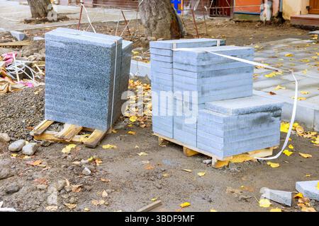 Zwei Stapel Pflastersteine, hellgrau, dunkelgrau, sind auf Holzpaletten auf der Baustelle gebündelt Stockfoto