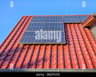 Solarpaneele eines Photovoltaik-Kraftwerks auf einem rot gekachelten Dach Stockfoto