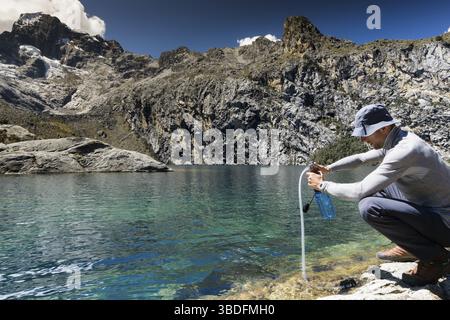 Bergsteiger pumpen und filtern Trinkwasser aus einem See in den Anden Perus während einer Kletterexpedition Stockfoto