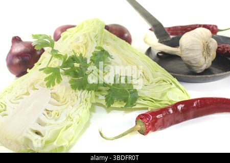 Spitzkohl mit Petersilie und Zwiebeln vor hellem Hintergrund Stockfoto