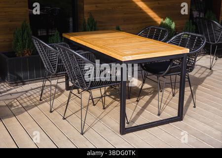 Esstisch aus Holz im Freien mit Metallstühlen im Innenhof oder auf der Terrasse, sonnenbeleuchtet Stockfoto