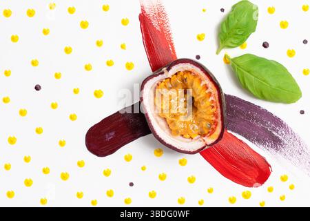 Einzelne Passionsfrucht in zwei Hälften auf einem abstrakten gemalten Hintergrund mit Pinselstrichen und gelbem Punkt, Cocktailzutat Stockfoto