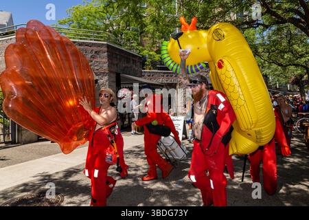 The Big Float, Portland, Oregon – 14. Juli 2018: Menschen in roten Anzügen ziehen mit aufblasbaren Meeresbewohnern an, um den Willamette River zu feiern. Stockfoto