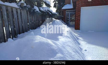 Der Fußweg und die Einfahrt waren mit tiefweißem Schnee bedeckt. Ein Wetter- oder Schneesturm-Konzept. Stockfoto