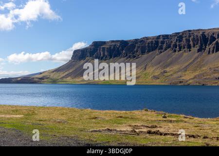 Landschaft des Hvalfjordur Fjords in Westisland (Vesturland) mit vulkanischen Bergen, felsigen Klippen und ruhigem Wasser in der Bucht an einem sonnigen Tag. Stockfoto
