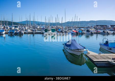 Eine lebendige Marina-Szene in Baiona Bay, Spanien, mit zahlreichen Booten und Yachten, die unter einem klaren blauen Himmel vertäut sind, ideal für Sommerreisen und Freizeit. Stockfoto