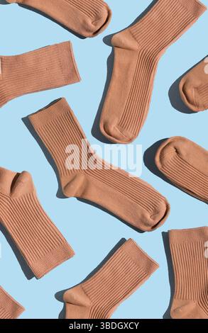 Anordnung von beigen Socken auf hellblauer Oberfläche, die verschiedene Texturen und Stile hervorheben, perfekt für Mode, Textildesign und kreative Projekte Stockfoto