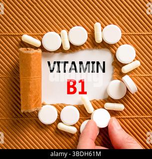 Vitamin B1-Symbol. Konzeptworte Vitamin B1 auf wunderschönem Weißbuch. Weiße Tabletten. Die Hand des Arztes. Schöner brauner Hintergrund. Medizinisch gesund Stockfoto