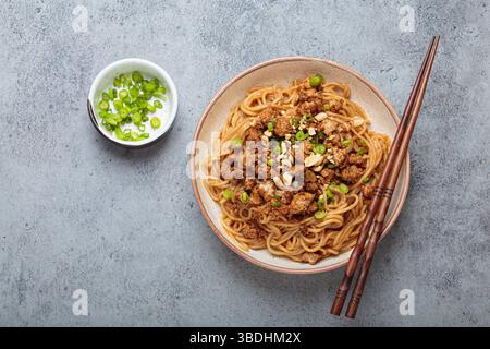Dan Dan Dan Nudeln serviert mit Essstäbchen und grünen Zwiebeln, traditionelles chinesisches Sichuan-Gericht Stockfoto