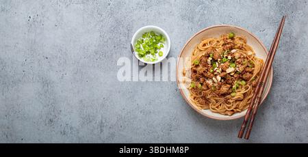 Dan Dan Dan Nudeln serviert mit Essstäbchen und grünen Zwiebeln, traditionelles chinesisches Sichuan-Gericht Stockfoto