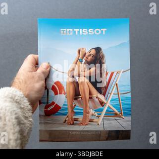 Paris, Frankreich - 10. März 2025: Eine Hand hält ein Tissot T-Spirit Magazin Nr. 3, das eine Frau im Badeanzug zeigt, die eine blaue Uhr trägt und auf einem Deck sitzt Stockfoto
