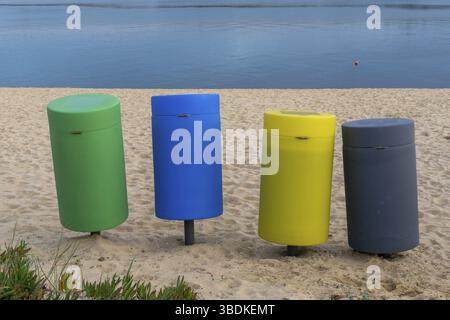 Vier bunte Mülltonnen an einem Sandstrand Stockfoto
