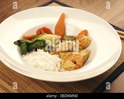 Red Thai Curry mit Huhn und Garnelen mit gebratenem Gemüse und Reis, gesundes Lebensmittelkonzept Stockfoto