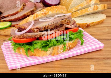 Salat-Sandwich aus Rinderbraten mit Zutaten auf Holzhintergrund Stockfoto