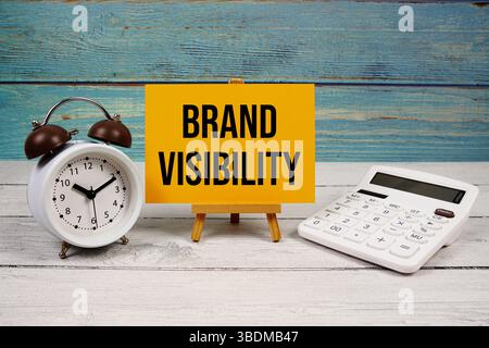 Markensichtbarkeit Text auf Papierkarte mit Taschenrechner und Wecker auf hölzernem Hintergrund geschrieben Stockfoto