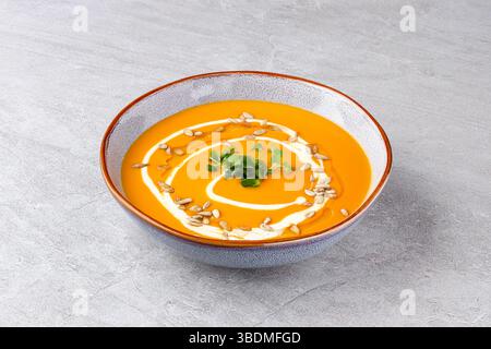 Eine samtige Suppe mit gerösteten Karotten und Kürbis, abgerundet mit einem Schuss Sahne, knusprigen Sonnenblumenkernen und frischem Mikrogrün für zusätzliche Textur A Stockfoto