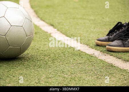 Fußball und Füße in Turnschuhen auf einem grünen Kunstrasen mit weißer Linienmarkierung, spielen Fußball Stockfoto