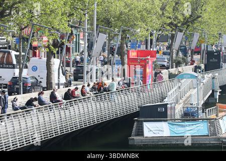 Dublin, Irland - 30. April 2025 - an einem sonnigen Nachmittag in der irischen Hauptstadt genießen die Menschen die Sonne entlang der Promenade des Flusses Liffey im Stadtzentrum von Dublin Stockfoto
