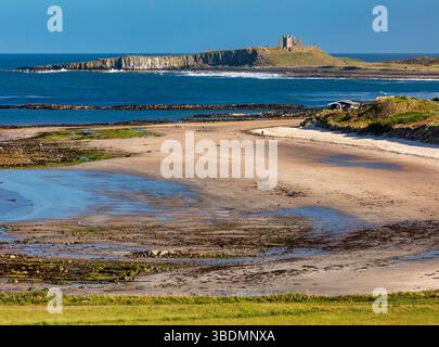 Blick im Frühling an einem sonnigen Tag mit Blick auf Dunstanburgh Castle an der Northumberland Coast von Low Newton-by-the-Sea bei Ebbe Stockfoto