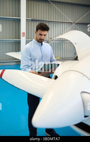 Flugzeugmechaniker mit digitalem Tablet bei der Inspektion des Flugzeugs im Hangar Stockfoto